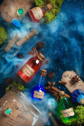 Colorful bottles of magical potions with handwritten labels, steam and oss on a dark wooden background. Fantasy concept with recipes and spells of beauty, luck and calmness.